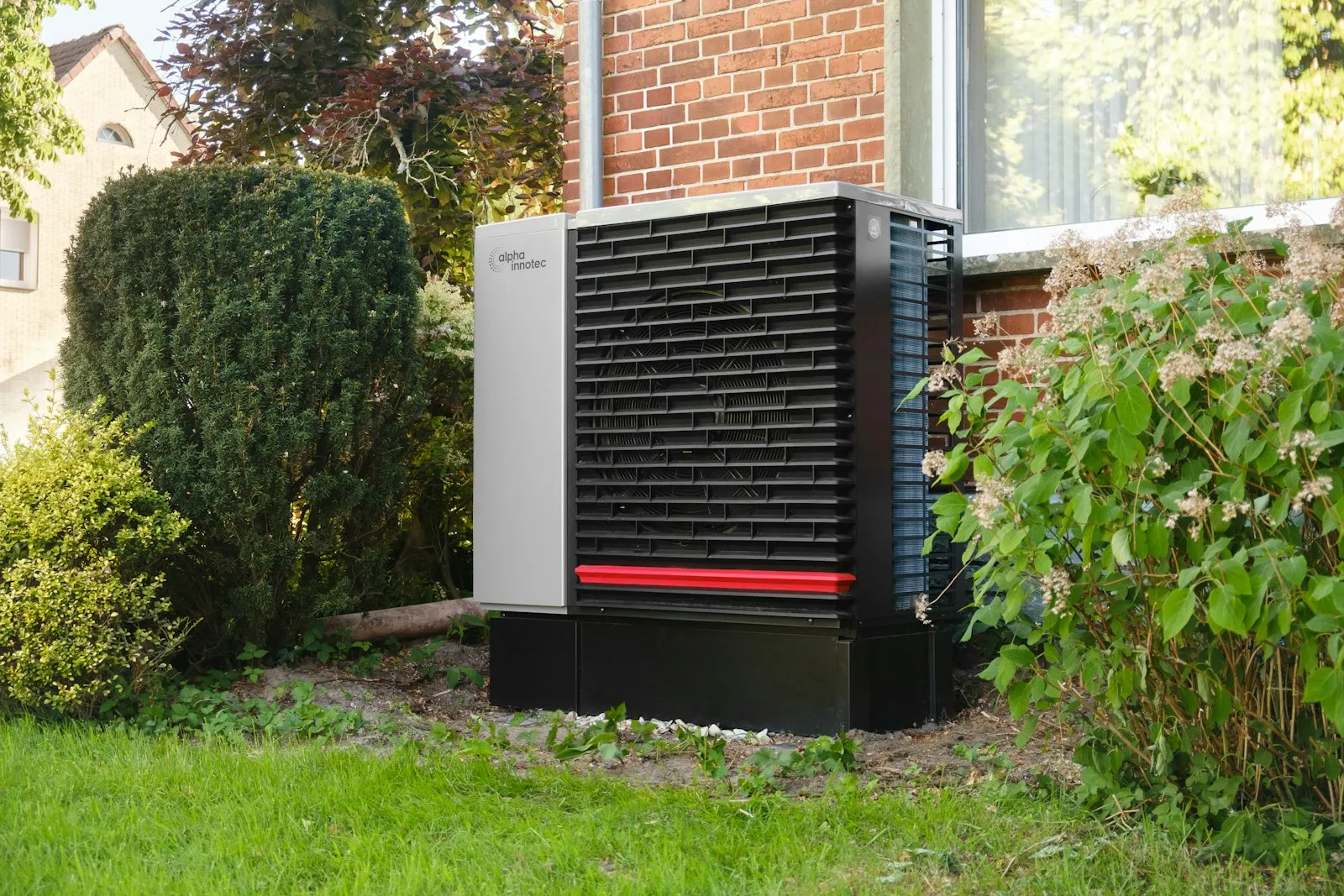 An air source heat pump outdoor unit fixed to the brick wall of a house