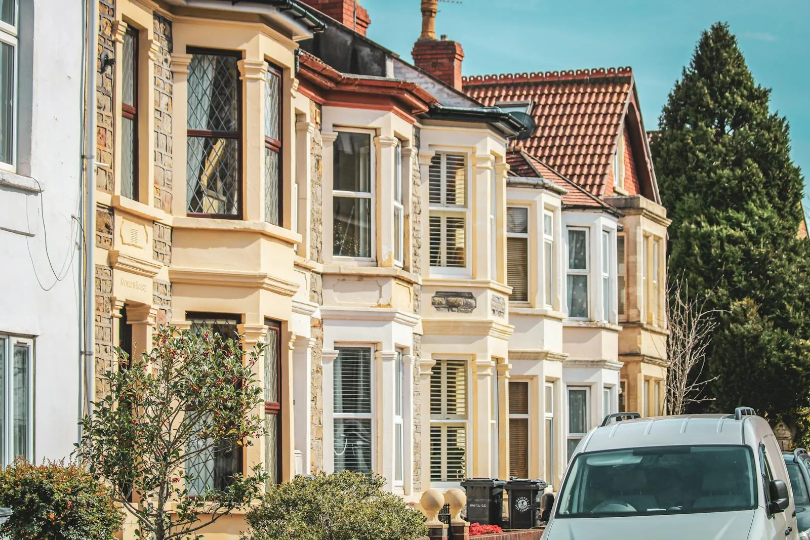 A row of late-Victorian terraced houses with cream-painted bay windows on a Bristol street — typical of the period housing stock that defines Redland.