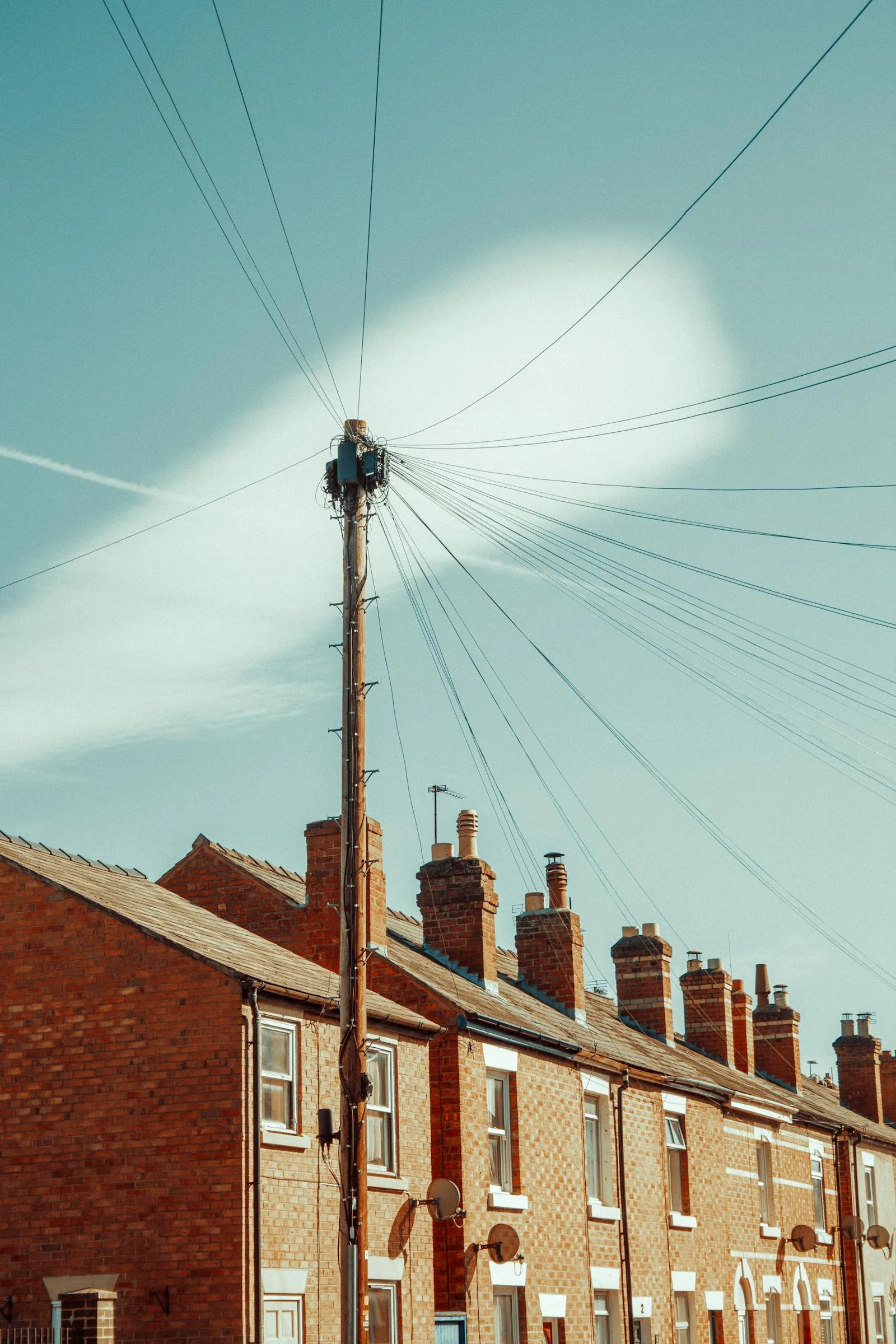 A row of UK brick terraced houses with chimney pots against blue sky — older terraced stock typical of UK market-town and village fringes, including parts of Thornbury and the wider South Gloucestershire area.